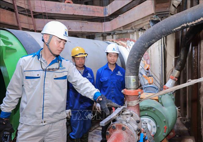Kỹ sư hướng dẫn công nhân vận hành hệ thống bơm bùn dưới giếng khoan ở độ sâu 12–15 m tại dự án xử lý nước thải TP Hà Nội. (Ảnh: Phan Phương/TTXVN)