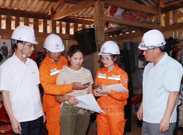 Cán bộ kỹ thuật Công ty Điện lực Lai Châu hướng dẫn người dân vào dùng điện thoại thông minh để thanh toán tiền điện hoặc tra cứu điện năng tiêu thụ của gia đình. (Ảnh: Quý Trung/TTXVN)