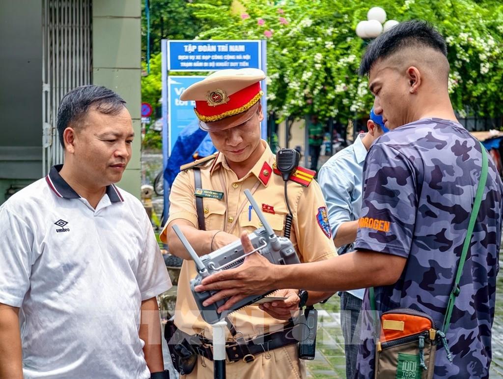 Cán bộ đội Cảnh sát giao thông số 7, Phòng Cảnh sát giao thông Hà Nội, mời người vi phạm xem lại hình ảnh từ thiết bị điều khiển UAV, đảm bảo tính chính xác, khách quan, minh bạch. Ảnh: Trung Nguyên - TTXVN