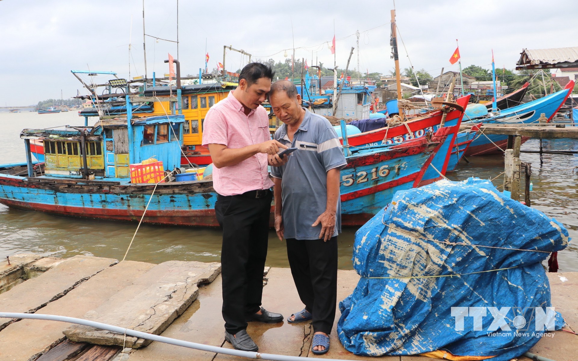 Bí thư Chi bộ thôn Hải Ninh, xã Bình Sơn (Quảng Ngãi) hướng dẫn đảng viên là ngư dân cách sử dụng "Sổ tay đảng viên điện tử". (Ảnh: Đinh Hương/TTXVN)