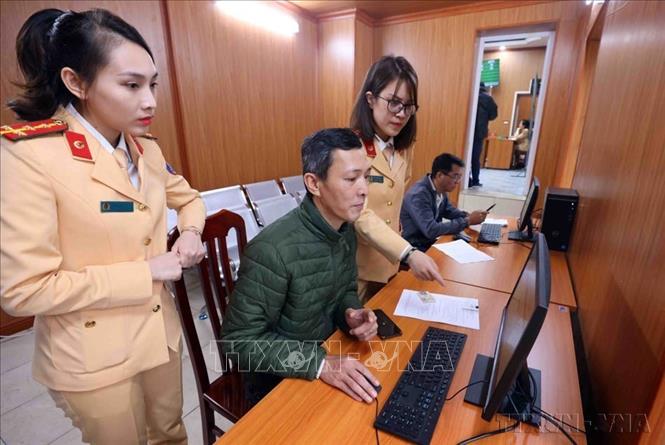 Cán bộ, chiến sĩ Đội Sát hạch, cấp giấy phép lái xe cơ giới đường bộ (Phòng CSGT, Công an TP Hà Nội) hướng dẫn người dân làm thủ tục đăng ký cấp, đổi giấy phép lái xe trên Cổng dịch vụ công quốc gia và ứng dụng VNeID. (Ảnh: Phạm Kiên/TTXVN)