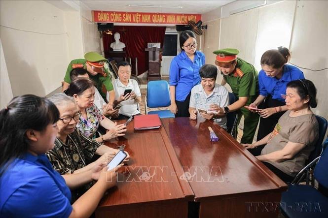 Lực lượng công an, cán bộ tổ dân phố, đoàn viên thanh niên hướng dẫn người dân phường Cửa Nam (Hà Nội) sử dụng các ứng dụng VNeID, iHanoi... trên điện thoại thông minh trong Chiến dịch "45 ngày đêm ra quân hỗ trợ hoạt động chuyển đổi số tại các xã, phường trong giai đoạn đầu vận hành mô hình chính quyền địa phương hai cấp". (Ảnh: Hoàng Hiếu/TTXVN)