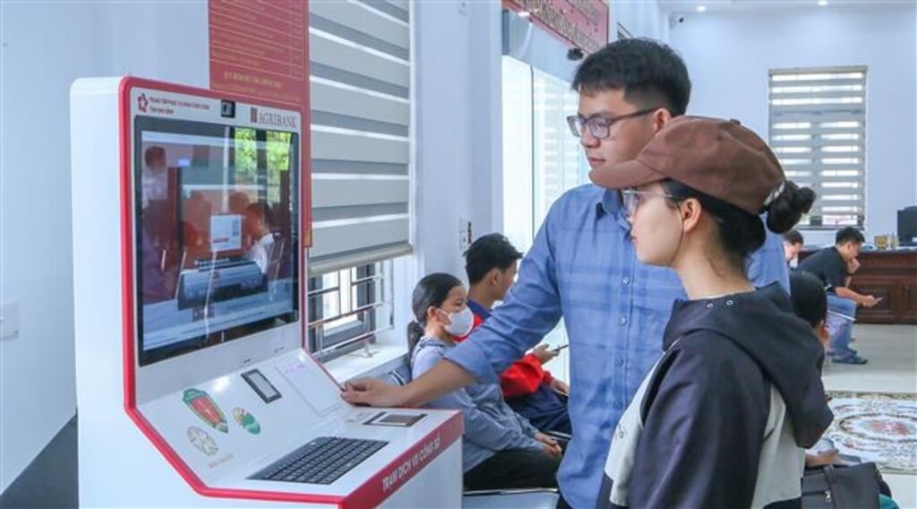 Cán bộ Trung tâm Phục vụ hành chính công xã Rạng Đông hướng dẫn người dân thực hiện thao tác tại Kiosk hành chính công. (Ảnh: Công Luật /TTXVN)