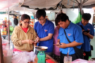 Tổ công nghệ số Đoàn Thanh niên xã Long Sơn cài đặt và hướng dẫn tiểu thương tại khu vực bán hàng hải sản phía trước Nhà lớn Long Sơn. (Ảnh: Đoàn Mạnh Dương/TTXVN)