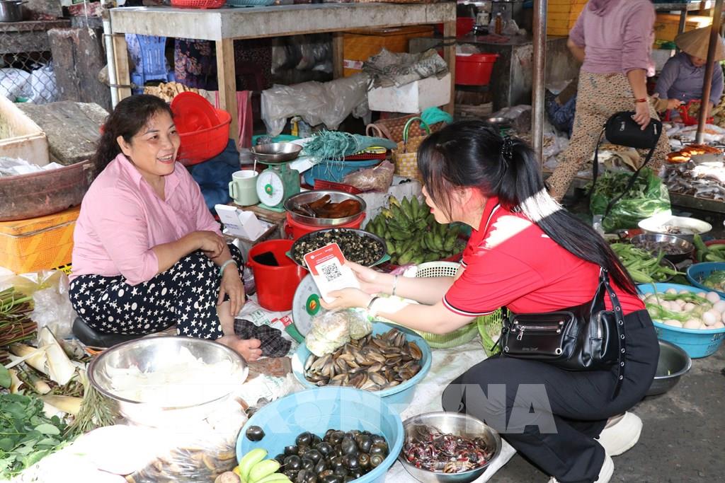 Hướng dẫn tiểu thương sử dụng bảng mã QR. (Ảnh: Thanh Hòa- TTXVN)