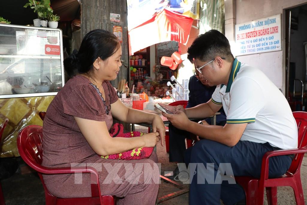 Tạo tài khoản ngân hàng cho tiểu thương chợ Nhị Long phục vụ việc thanh toán không dùng tiền mặt. (Ảnh: Thanh Hòa- TTXVN)