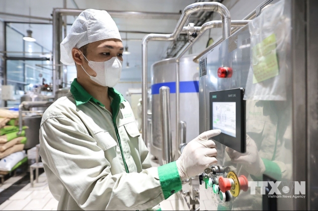 Nhân viên kỹ thuật kiểm tra, theo dõi hoạt động của thiết bị trong dây chuyền sản xuất. (Ảnh: Lê Đông/TTXVN)