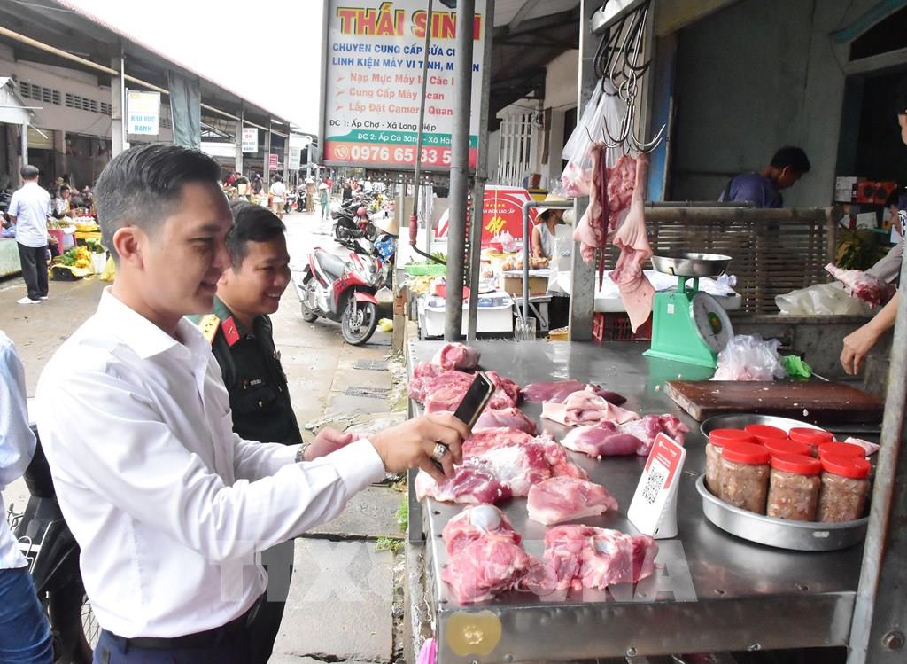 Nhà chức trách xã Long Hiệp tuyên truyền, hướng dẫn tiểu thương thực hiện thanh toán không dùng tiền mặt tại Chợ Long Hiệp. (Ảnh: Thanh Hòa – TTXVN)