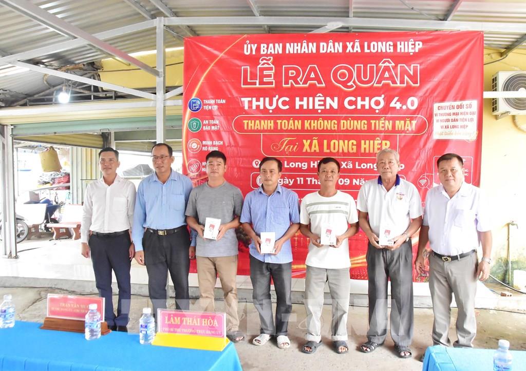 Lãnh đạo xã Long Hiệp trao thiết bị bảng QR và loa thông báo cho tiểu thương trong ngày ra quân triển khai