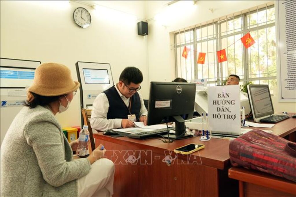 Cán bộ Trung tâm Phục vụ hành chính công phường Xuân Hương - Đà Lạt giải quyết thủ tục hành chính cho người dân lớn tuổi chưa quen sử dụng công nghệ. (Ảnh: Chu Quốc Hùng/TTXVN)