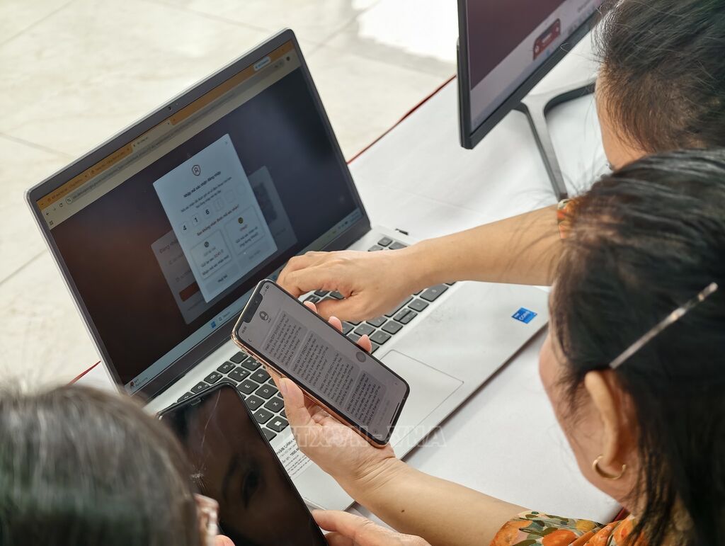 Thành viên Tổ chuyển đổi số cộng đồng hướng dẫn người dân tiếp cận, sử dụng các tiện ích số. (Ảnh: Trung Nguyên/TTXVN)