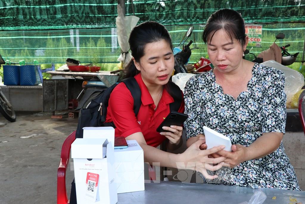 Hướng dẫn tiểu thương chợ Cầu Xây sử dụng bảng mã QR. (Ảnh: Thanh Hòa - TTXVN) Hướng dẫn tiểu thương chợ Cầu Xây sử dụng bảng mã QR. (Ảnh: Thanh Hòa - TTXVN)