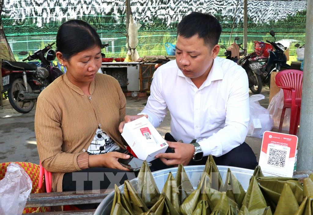 Đại diện Viettel trao và hướng dẫn tiểu thương chợ Cầu Xây sử dụng bảng mã QR. (Ảnh: Thanh Hòa - TTXVN) Đại diện Viettel trao và hướng dẫn tiểu thương chợ Cầu Xây sử dụng bảng mã QR. (Ảnh: Thanh Hòa - TTXVN)