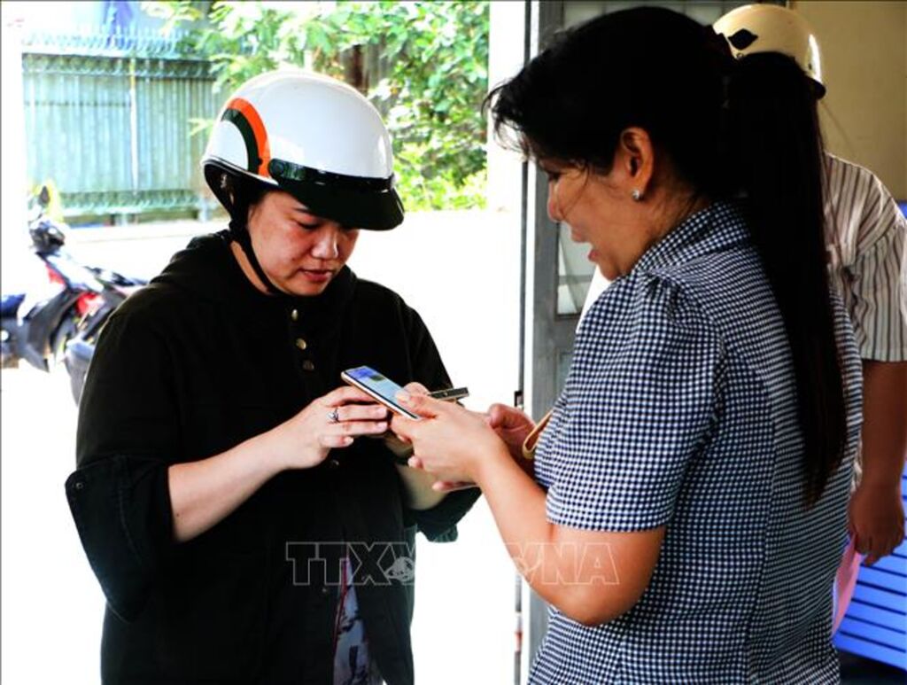 Bà Vũ Thị Thúy Hằng, Trưởng khu vực 5 (phường Vị Tân, thành phố Cần Thơ) hướng dẫn người dân sử dụng điện thoại thông minh thực hiện dịch vụ công trực tuyến. (Ảnh: Duy Khương/TTXVN)