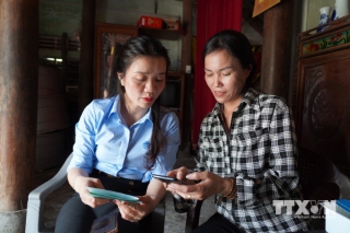 Hướng dẫn người dân cài đặt phần mềm, kê khai thông tin trên phần mềm điện thoại di động. (Ảnh: Thanh Thuỷ/TTXVN)