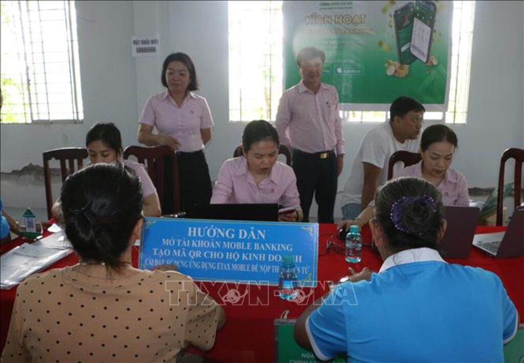 Tư vấn trực tiếp, giúp các hộ buôn bán nhỏ lẻ mở tài khoản thanh toán và tạo mã QR để niêm yết tại cửa hàng. (Ảnh: Duy Khương/TTXVN)