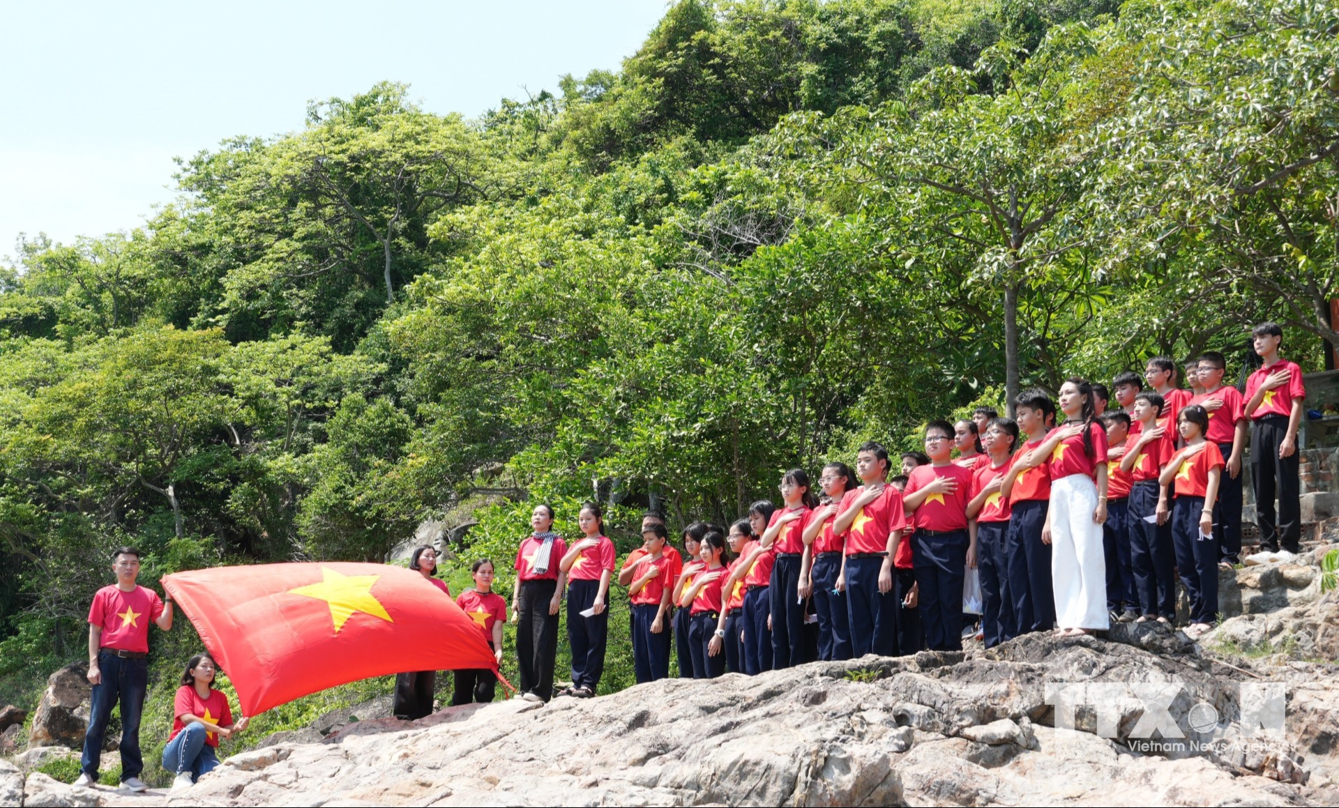 Học sinh chào cờ ở khu vực đèo Hòn Hèo, phường Đông Ninh Hòa sau khi học tập các bài học lịch sử có ứng dụng AI tại trường. (Ảnh: Phan Sáu/TTXVN)