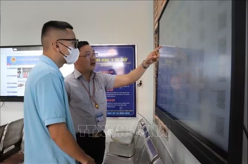 Giám đốc Trung tâm Phục vụ hành chính công xã Tầm Vu - Nguyễn Tuấn Anh hướng dẫn người dân quét mã tra cứu thông tin. (Ảnh: Đức Hạnh/TTXVN).