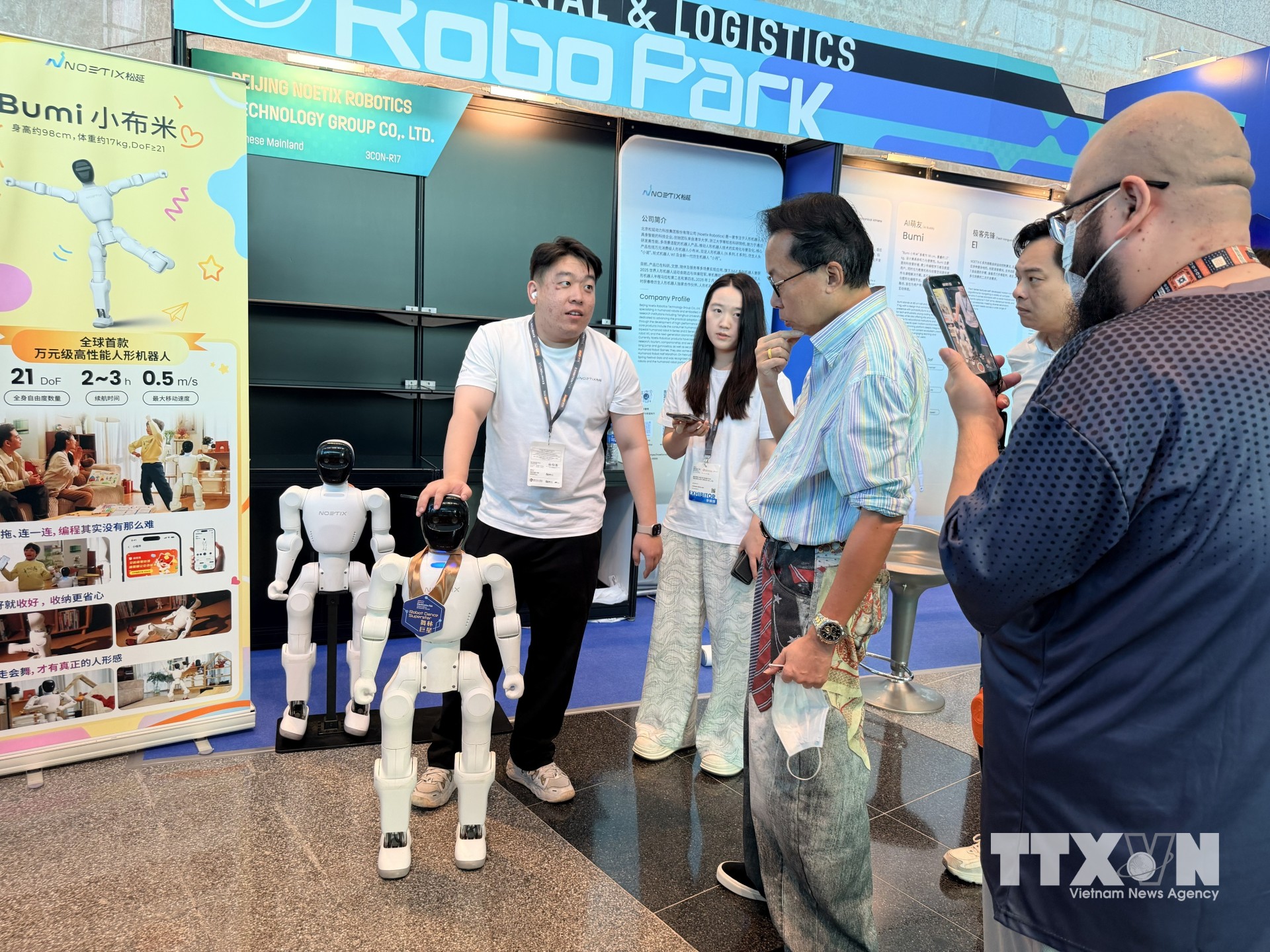 Khách tham quan triển lãm thử nghiệm giao lưu với robot. (Ảnh: Lê Anh/TTXVN)