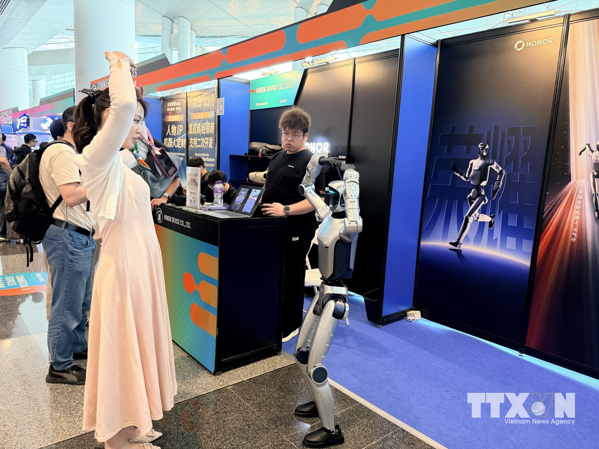 Khách tham quan triển lãm thử nghiệm giao lưu với robot. (Ảnh: Lê Anh/TTXVN)