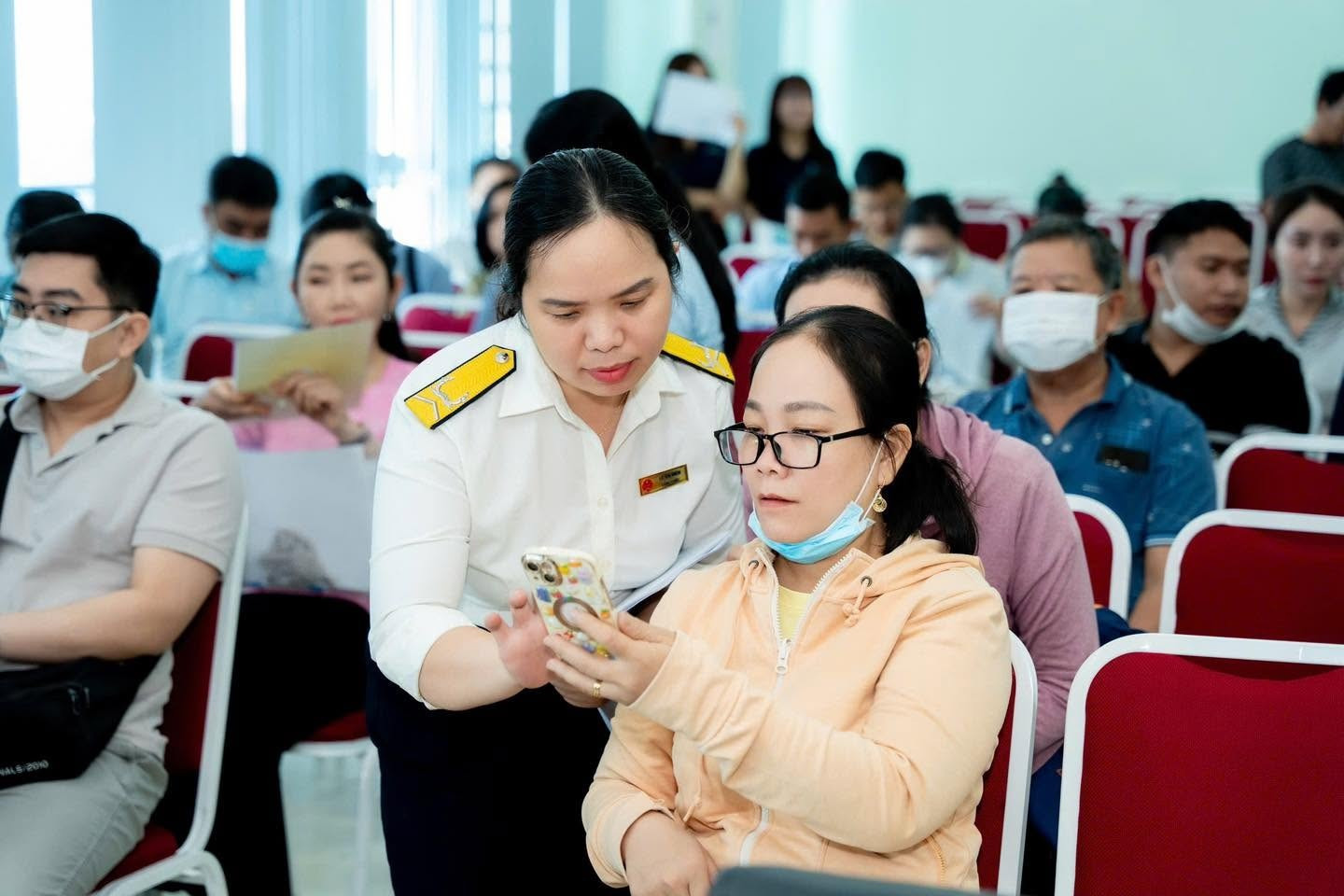Cán bộ thuế TP Hồ Chí Minh hướng dẫn người dân sử dụng các ứng dụng số khi kê khai thuế trên nền tảng số. (Ảnh: Hoàng Tuyết/Báo Tin tức và Dân tộc)